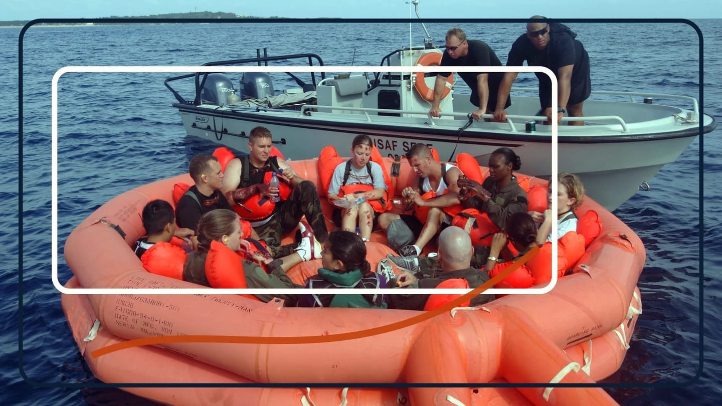 Lifejacket-wearing people sit in an orange inflatable life raft beside a rescue boat