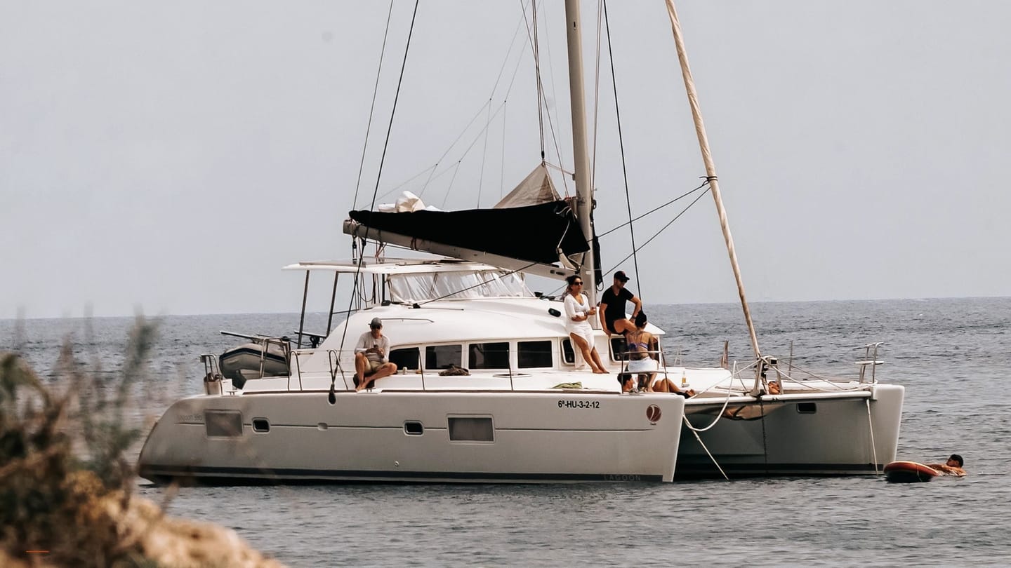 People relaxing aboard an anchored sailboat on calm water