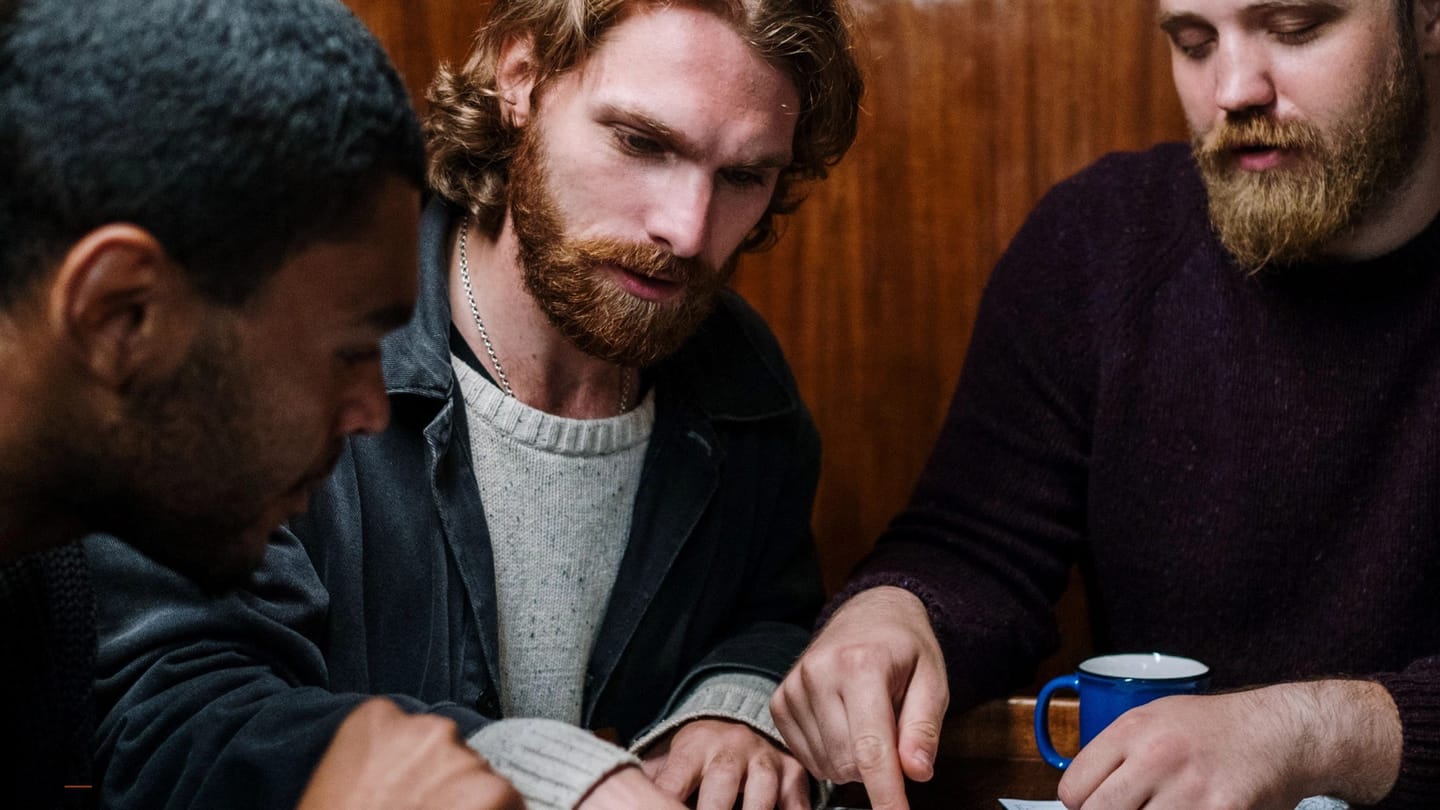 Crew comparing notes over a chart at the saloon table