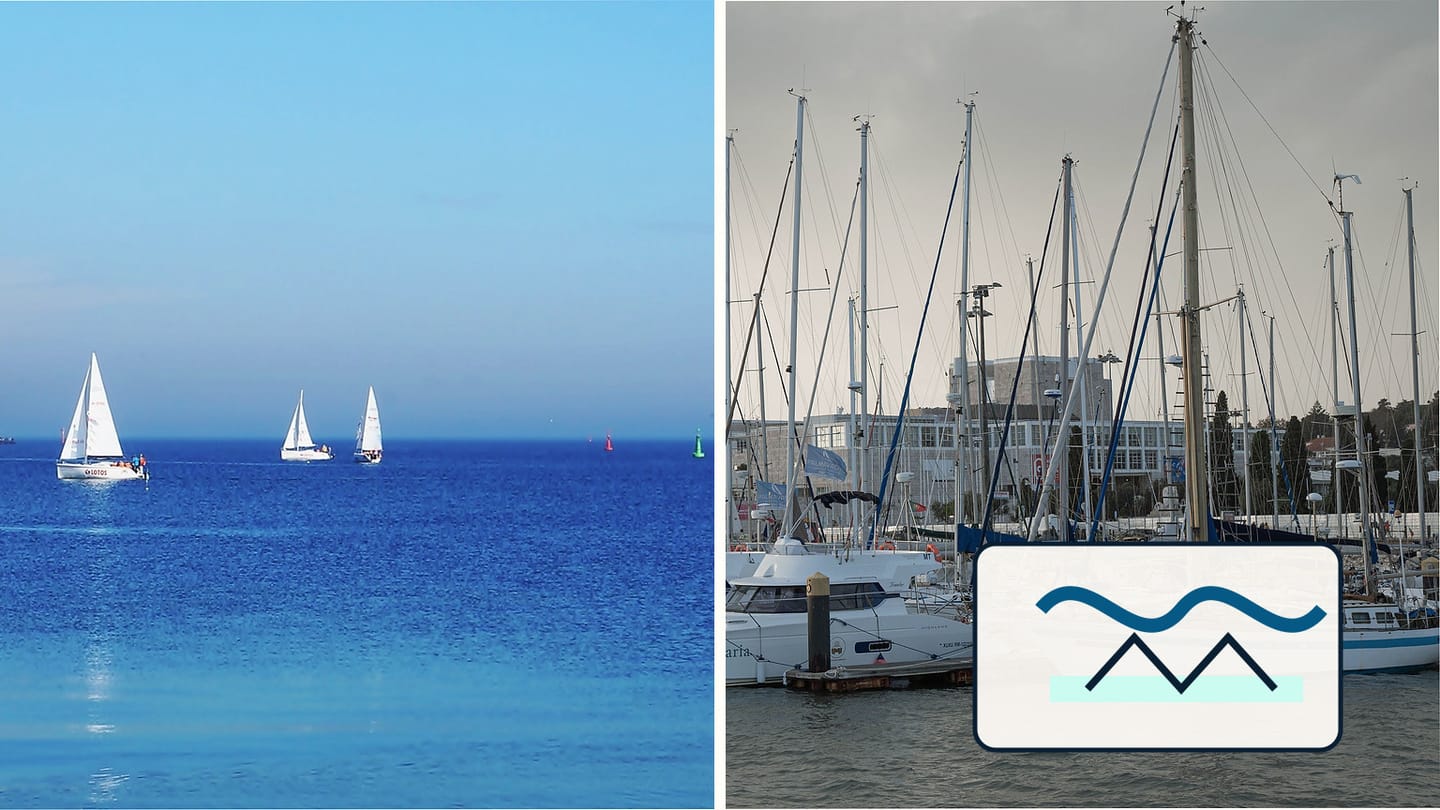 Sailboats on open blue water beside yachts moored in a marina