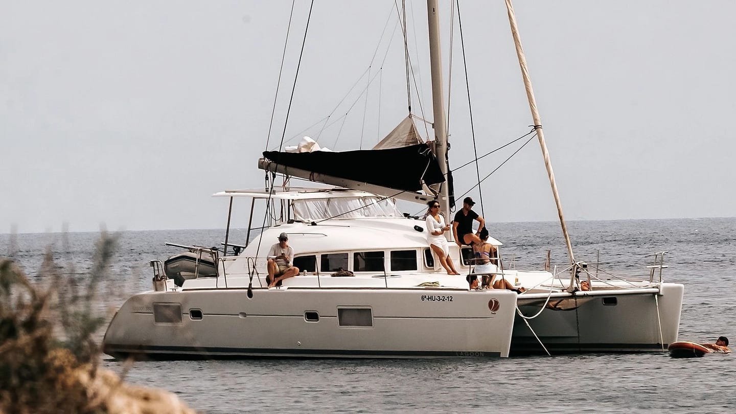 Sailboat anchored near shore with people aboard
