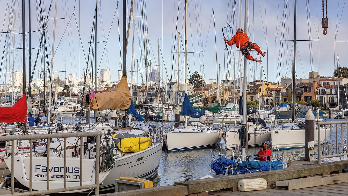 Technician working between sailboats in a yard