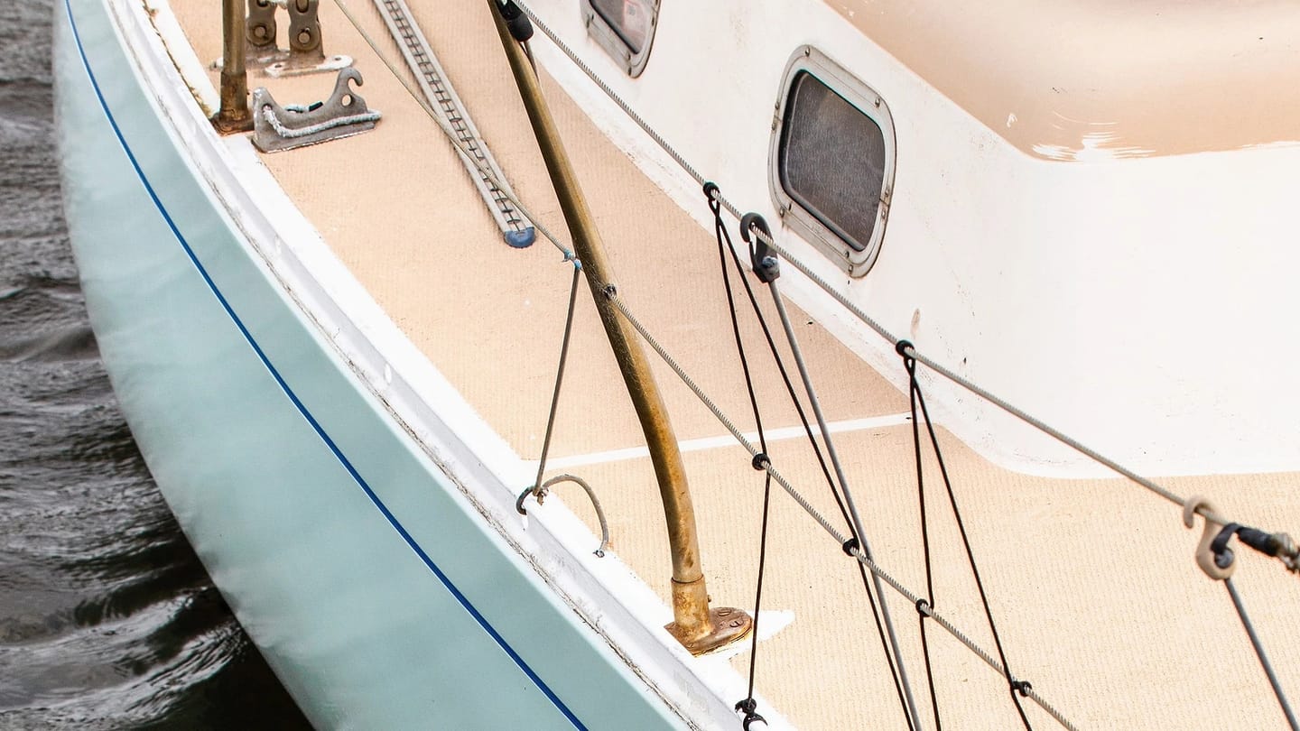 Close view of a white sailboat hull beside the water