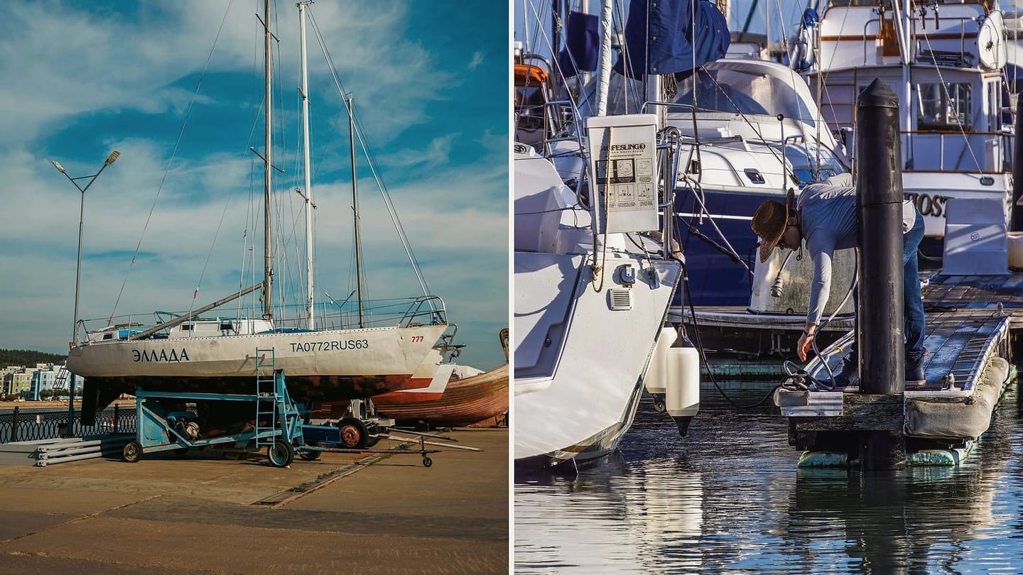 Sailboat supported ashore beside a person working on a docked sailboat