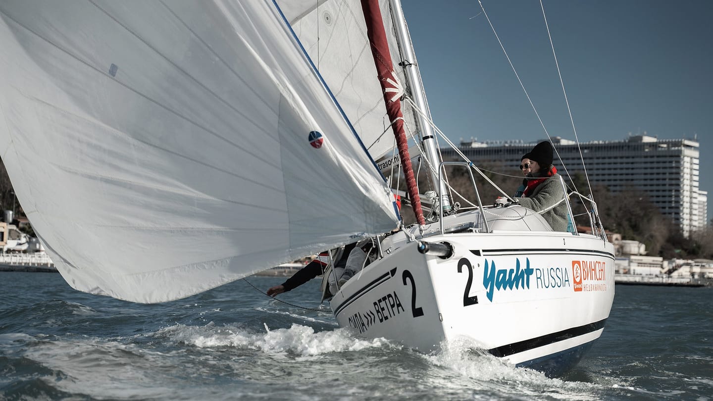 A white sailing yacht heels in moderate wind on open water.