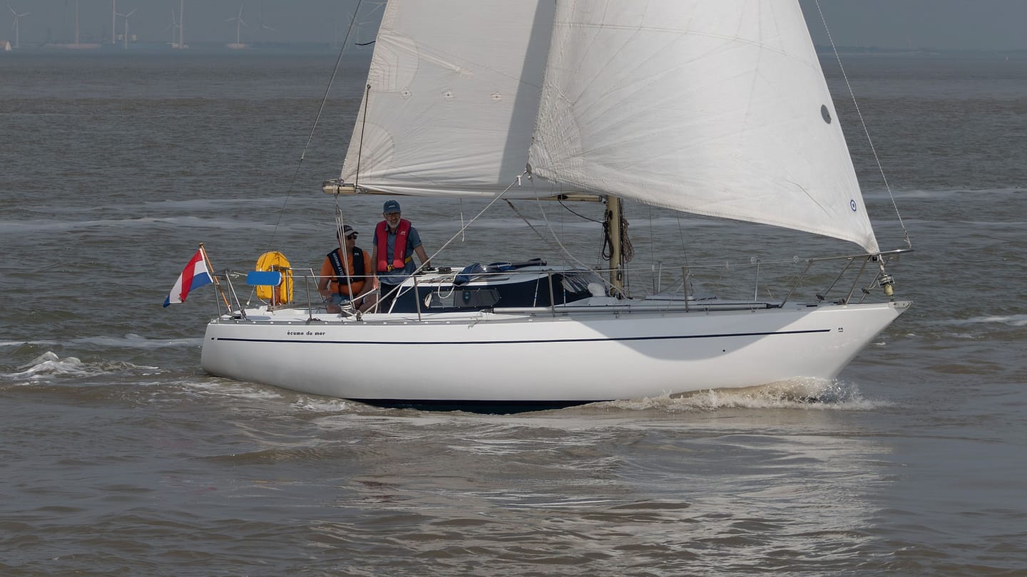 A sailing yacht seen from the side with its sails drawing and hull heeled.