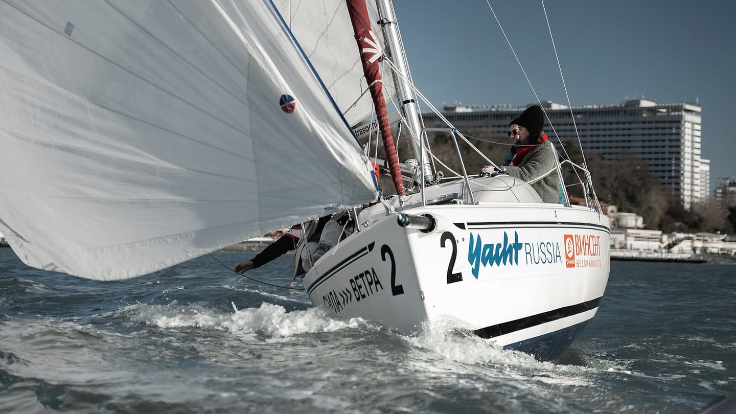 A ballasted sailing yacht moves through waves with its keelboat hull heeled.