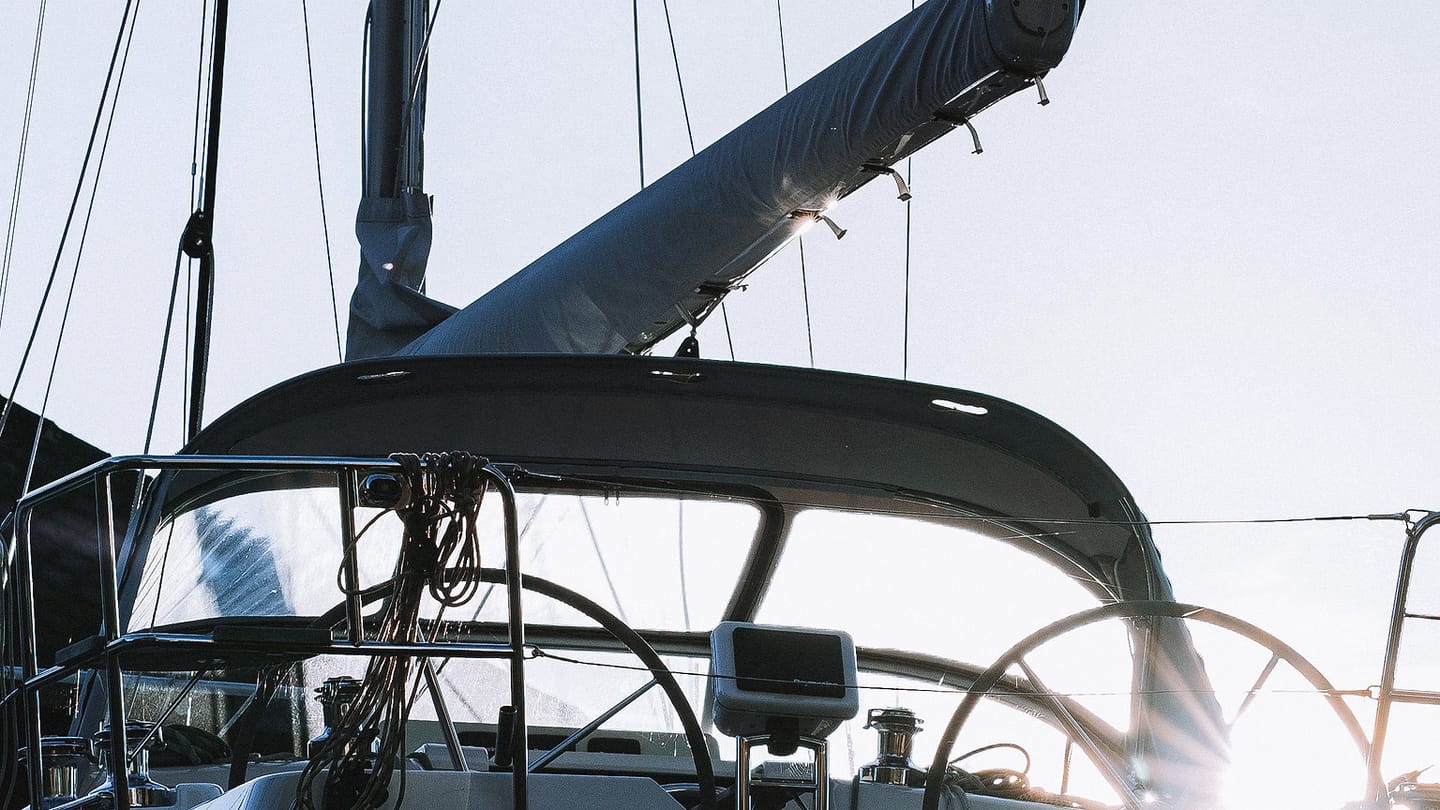 A moored white sailboat is seen close to its hull and deck at a dock.
