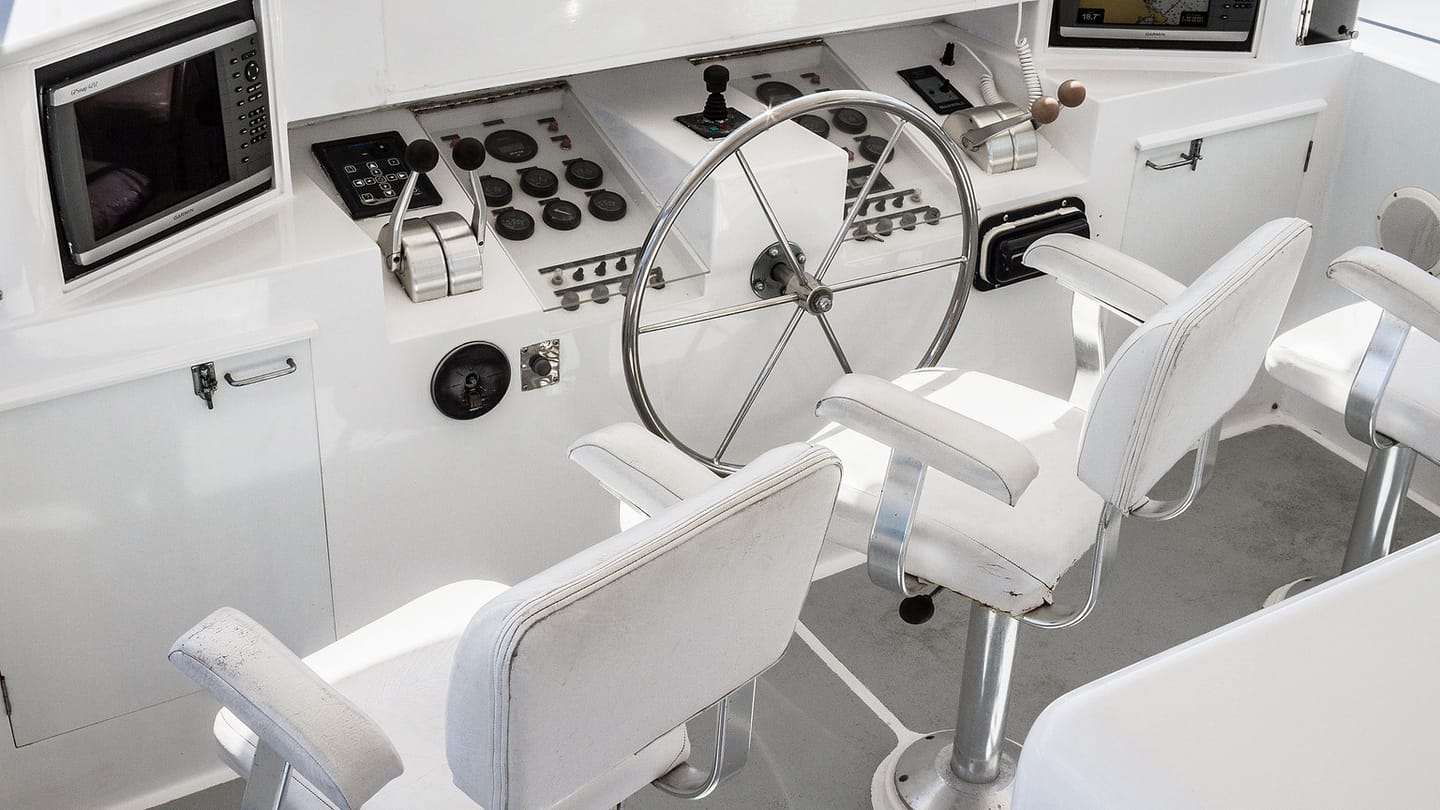 A marine helm console contains analogue gauges and electronic displays.