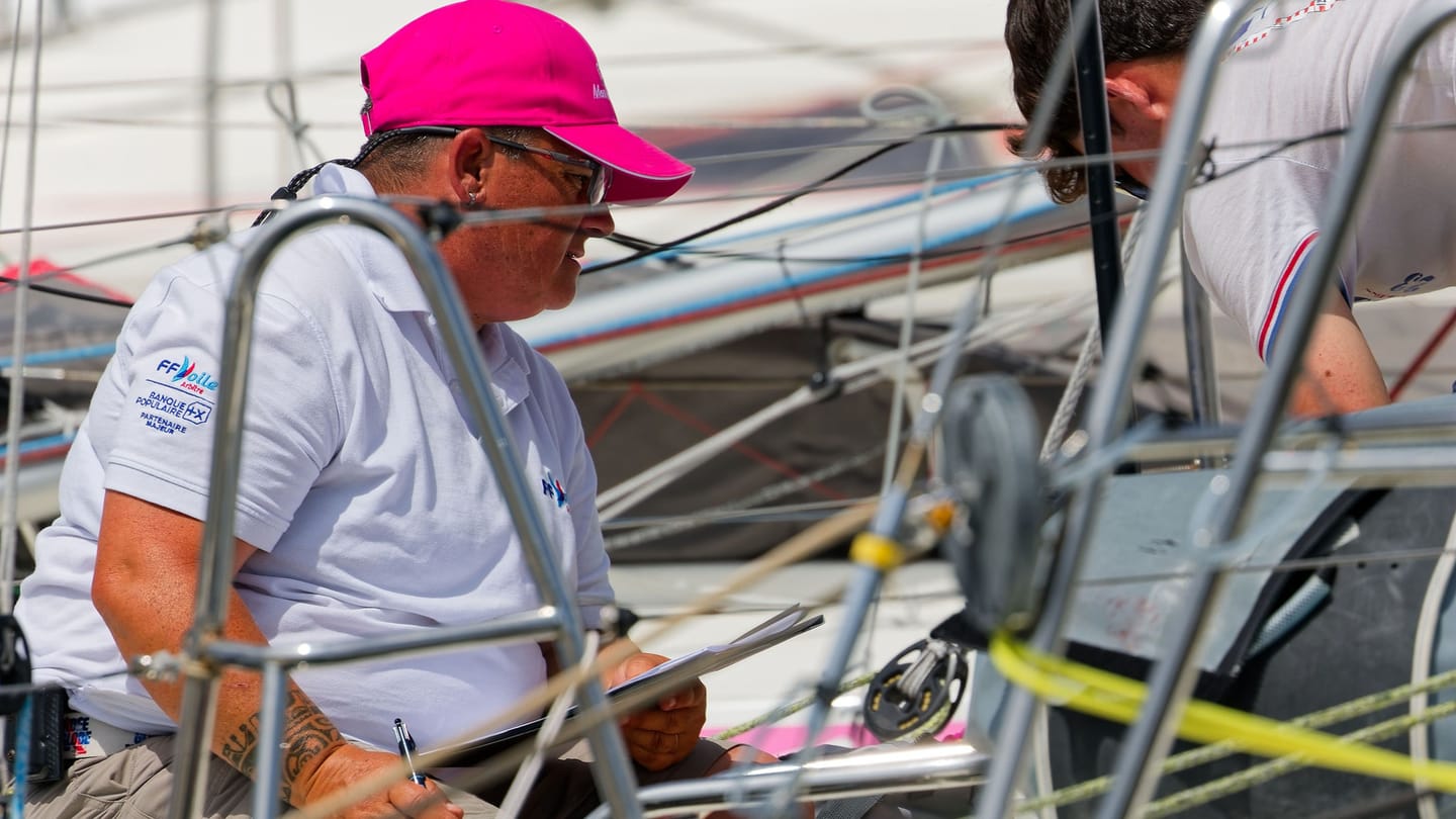 A sailing crew working together on the deck of a sailboat