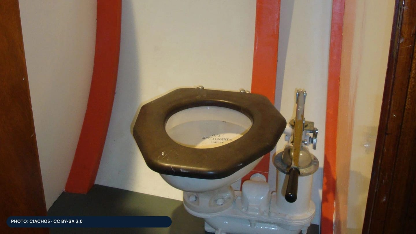 A white yacht toilet mounted against a wood-panelled cabin wall
