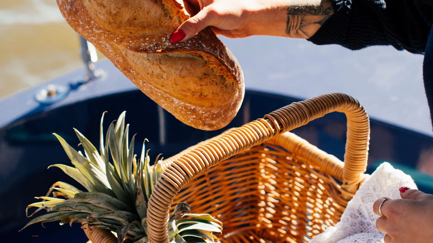 Person carrying a basket filled with food aboard a yacht