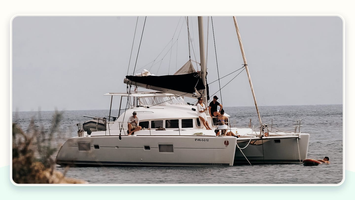 A crewed yacht at anchor with guests relaxing in the cockpit