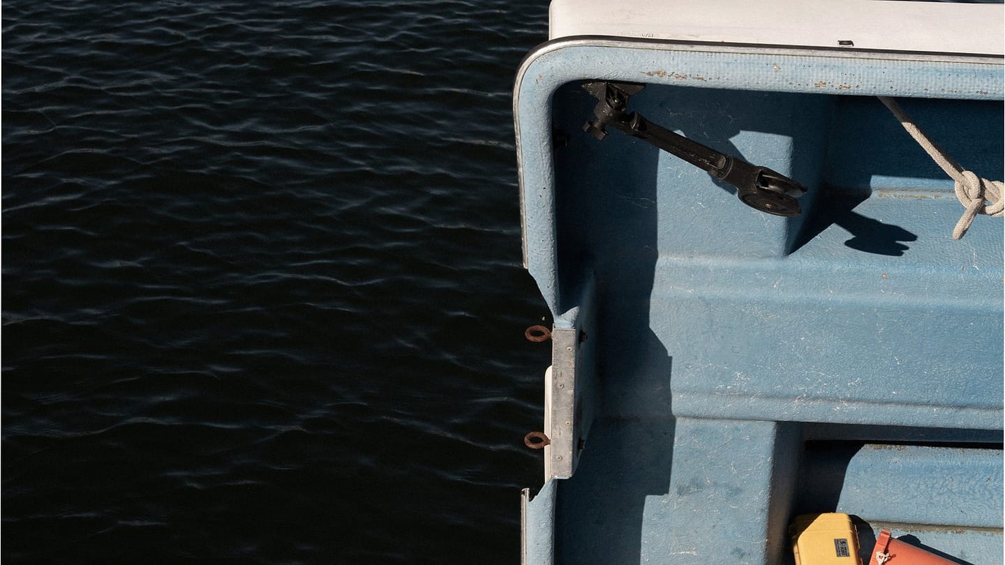 An open deck hatch on a sailboat with water alongside
