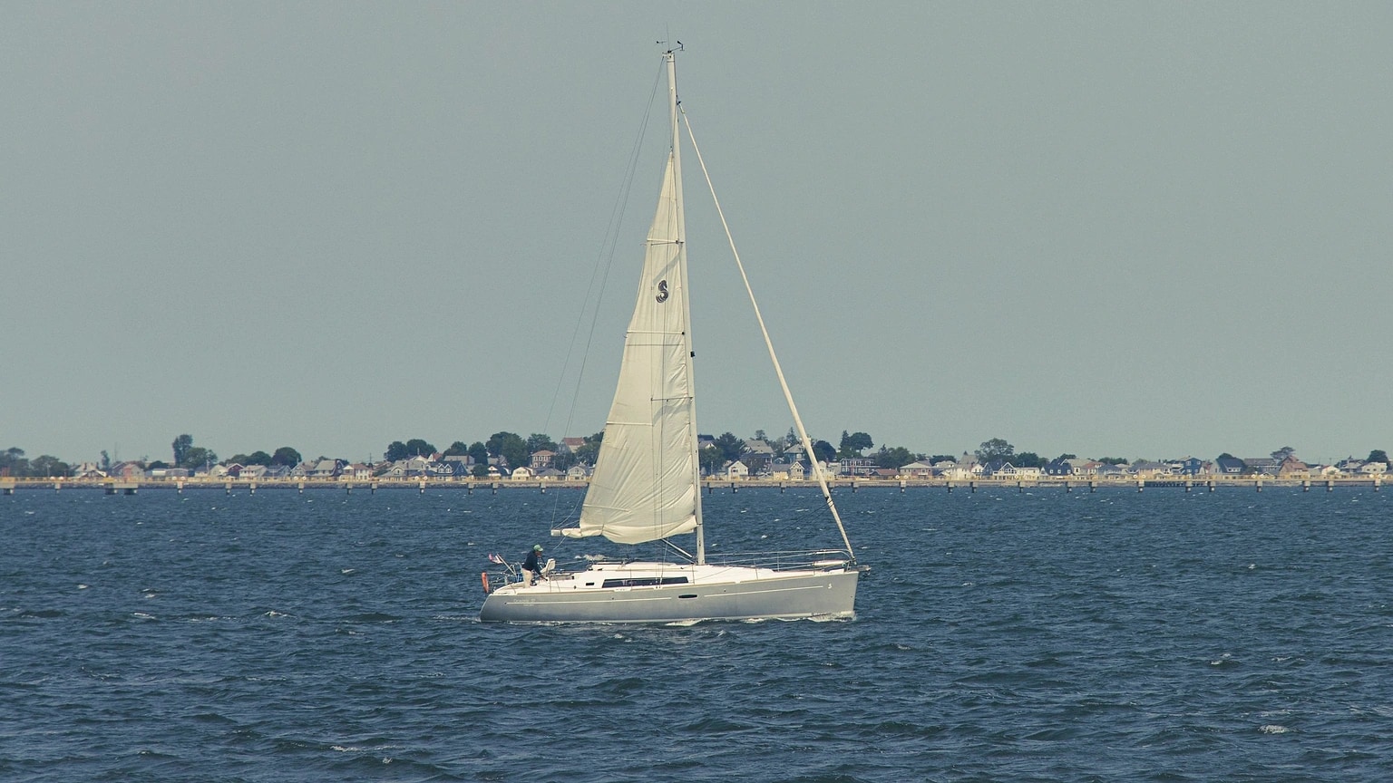 Sailboat underway near a wooded shoreline