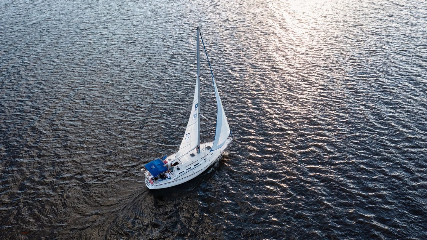 Lone sailing yacht making way across broad open water