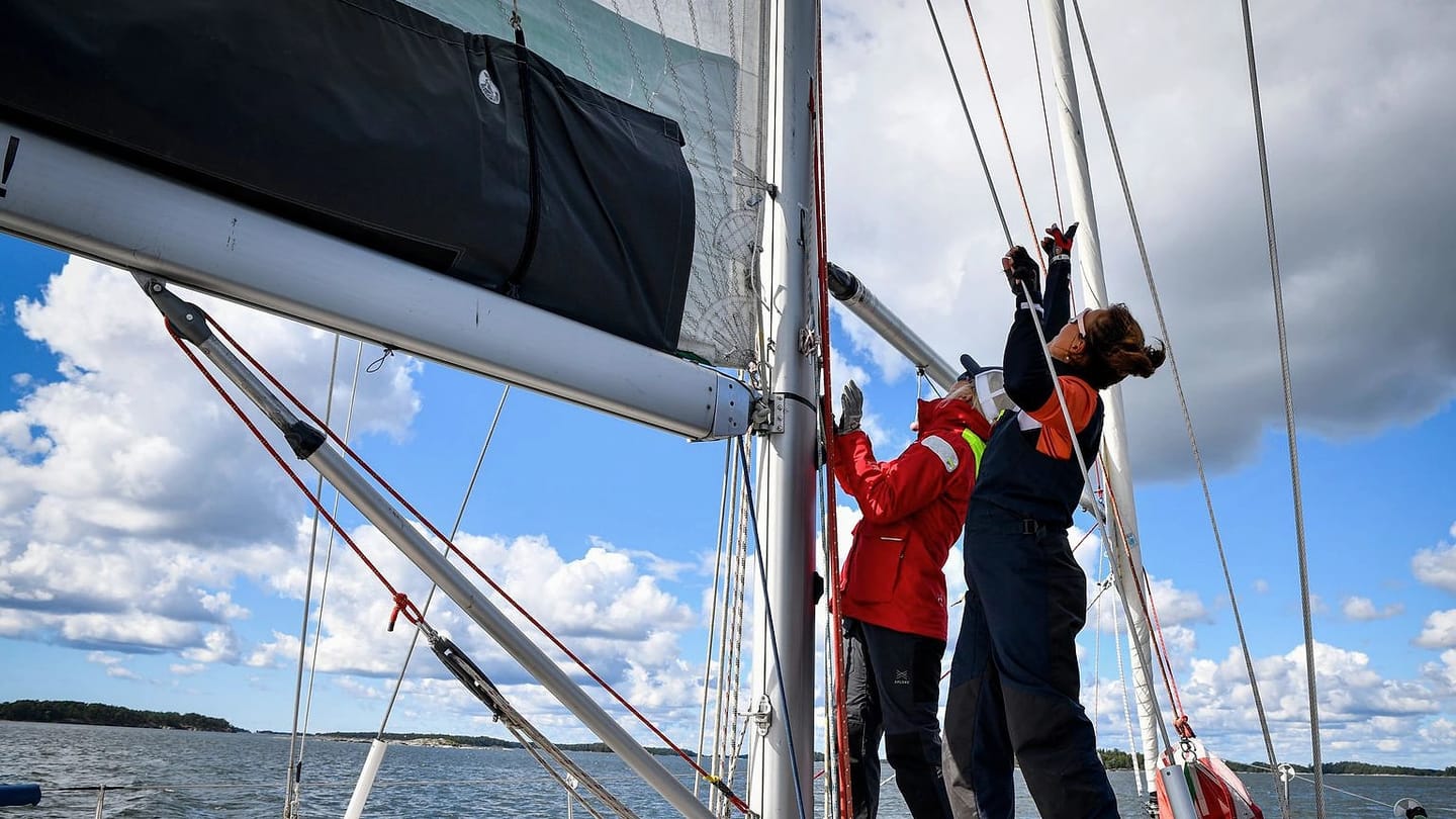 Sailing crew handling lines and sails on a yacht deck