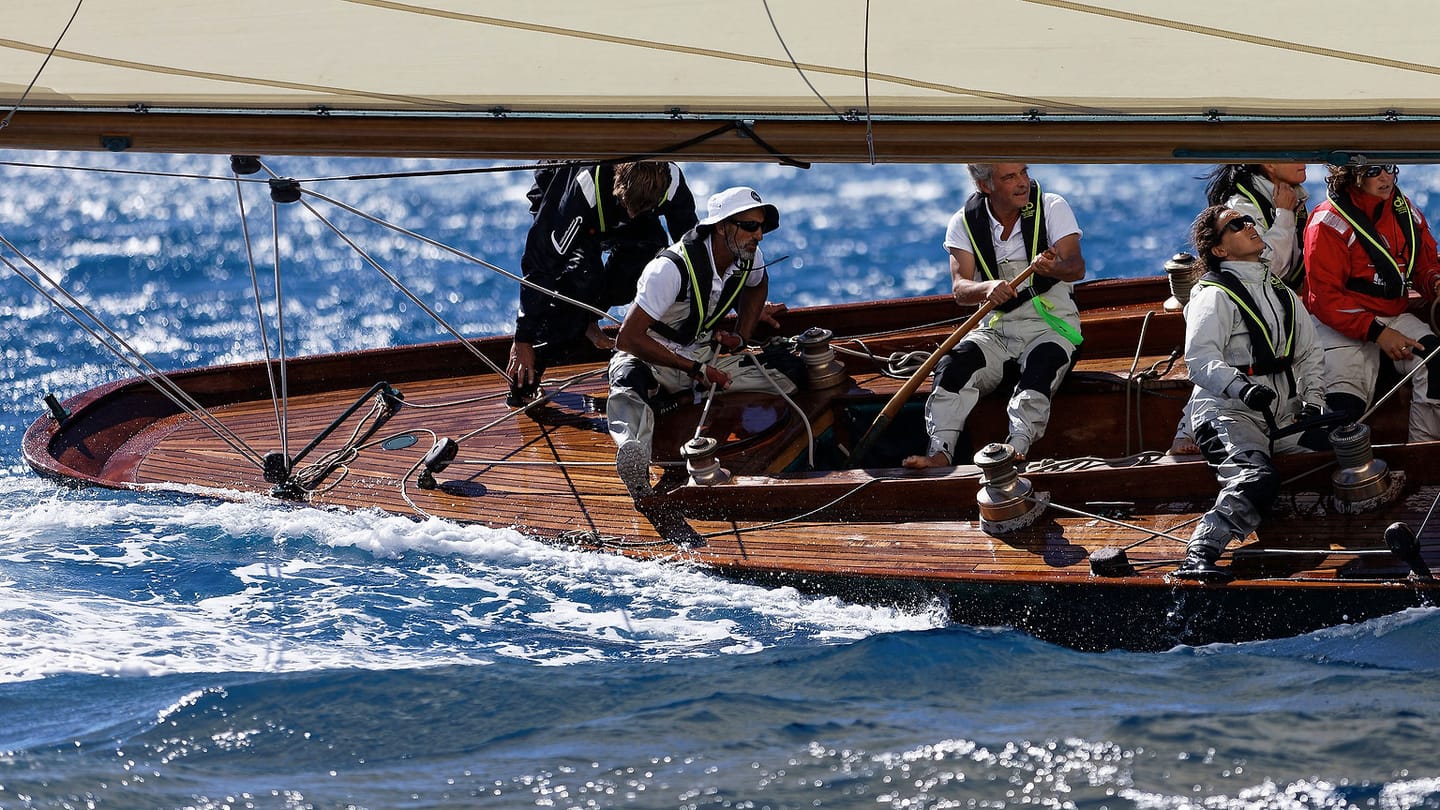 A sailing crew working together on the deck of a heeled yacht