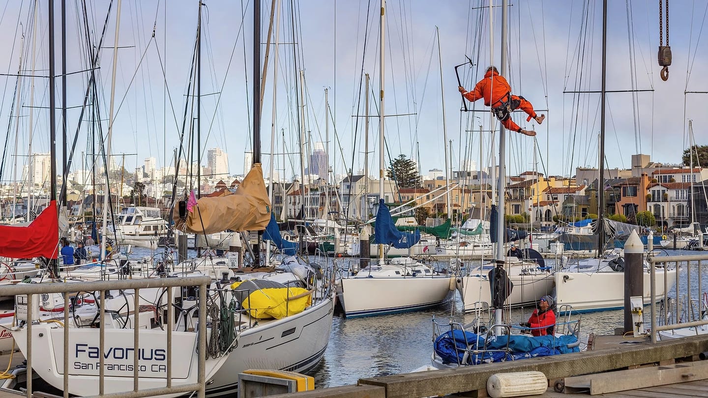 Technician working on equipment beside sailboats
