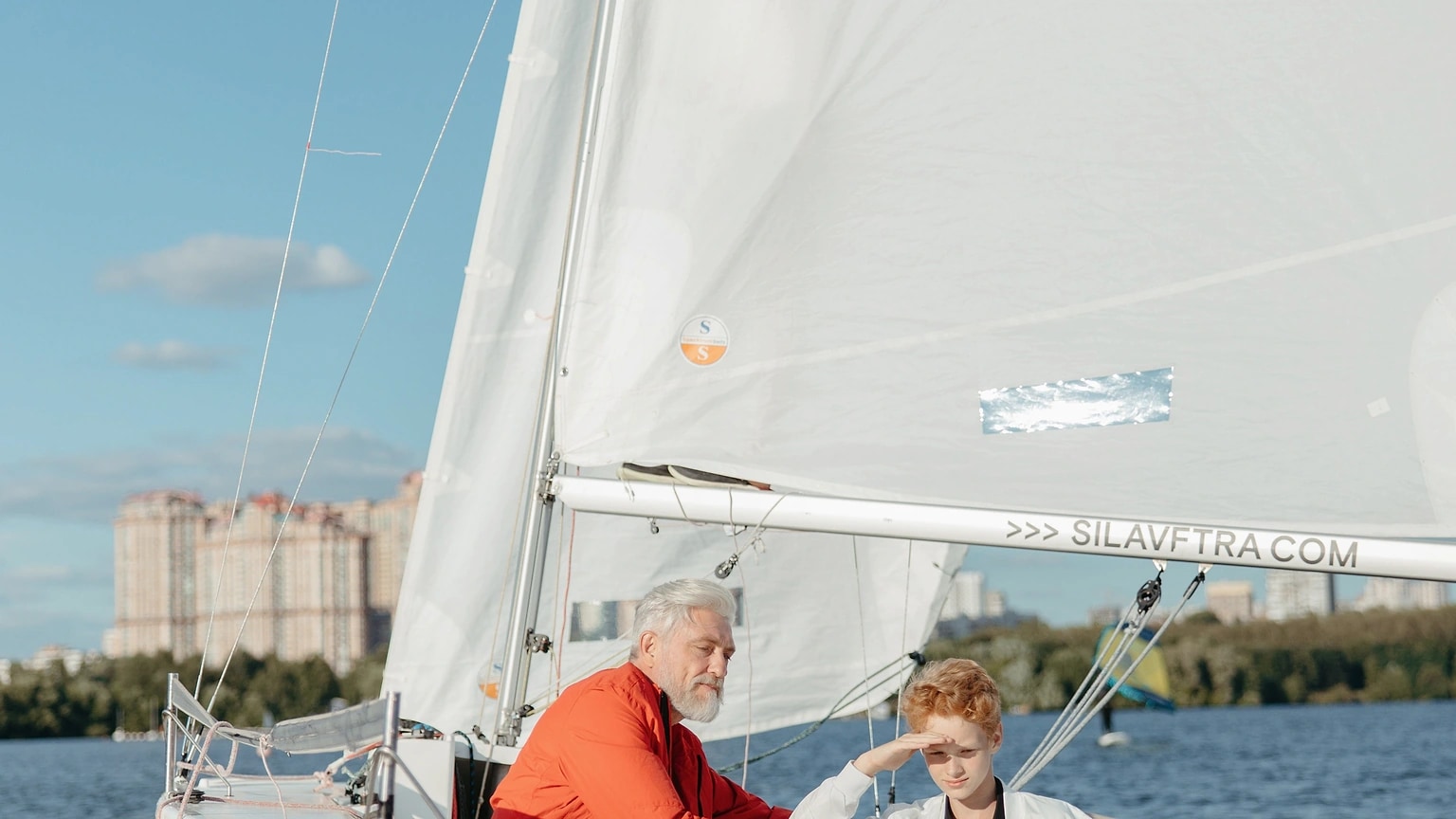 Sailor steering a small sailboat in open water