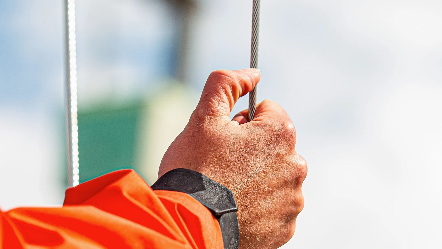 Hand holding a sailing line beside the mast