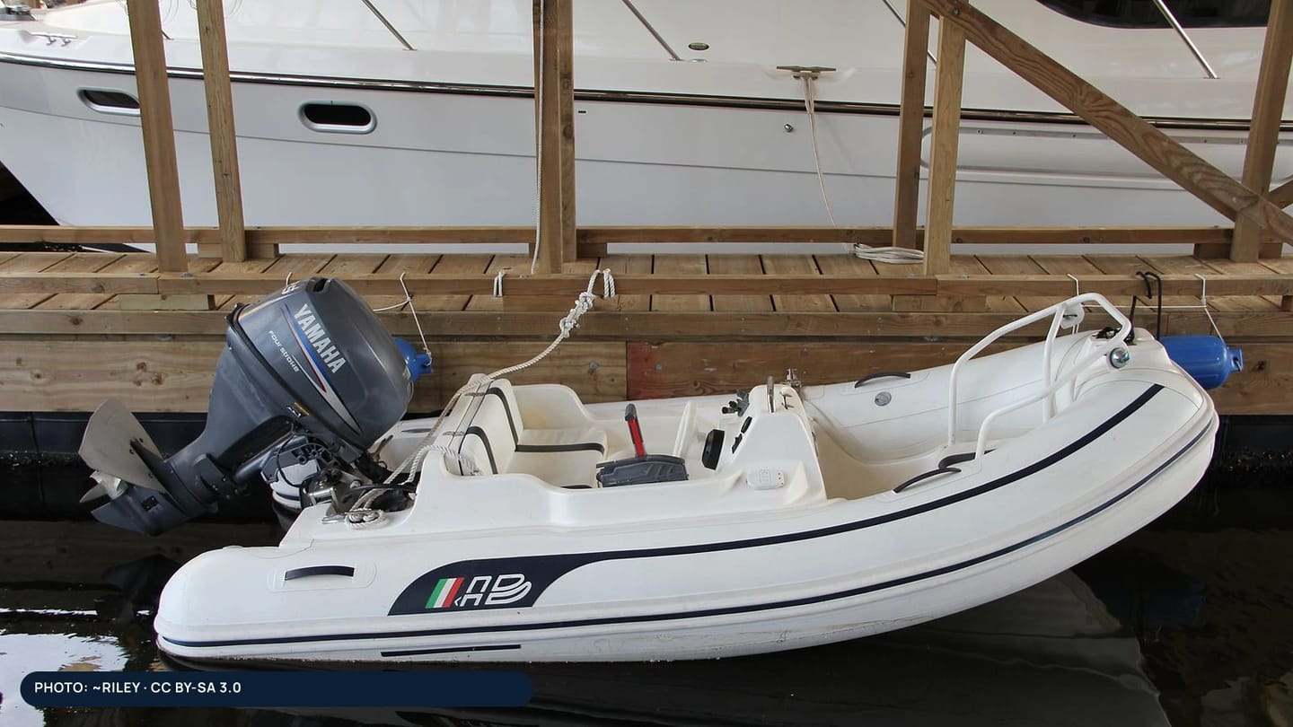 A rigid inflatable dinghy with an outboard secured beside a dock