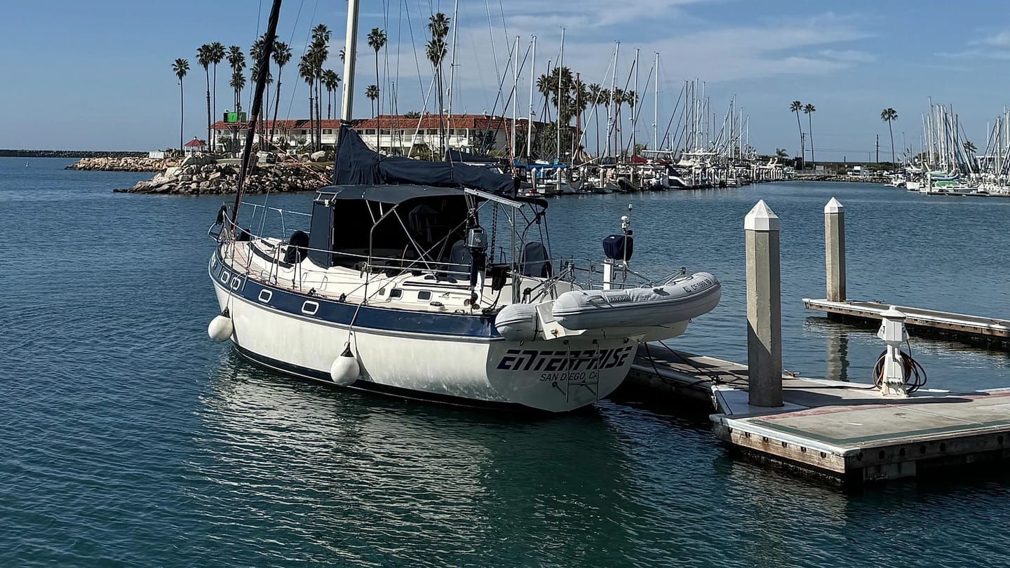 A sailboat lies alongside a dock in a marina.