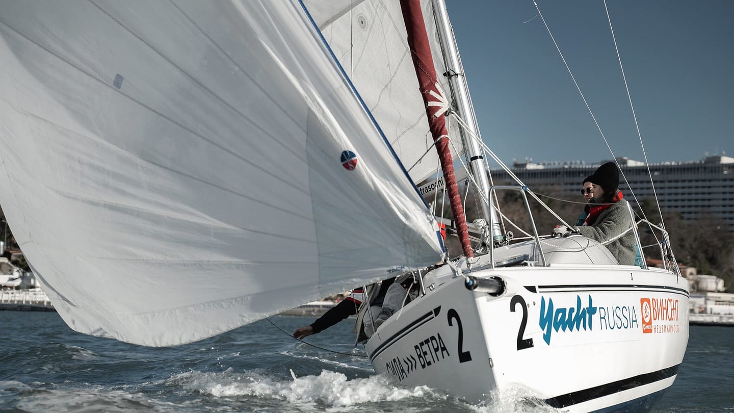 A sailboat viewed from the side holds a clear sailing angle rather than pointing straight downwind.