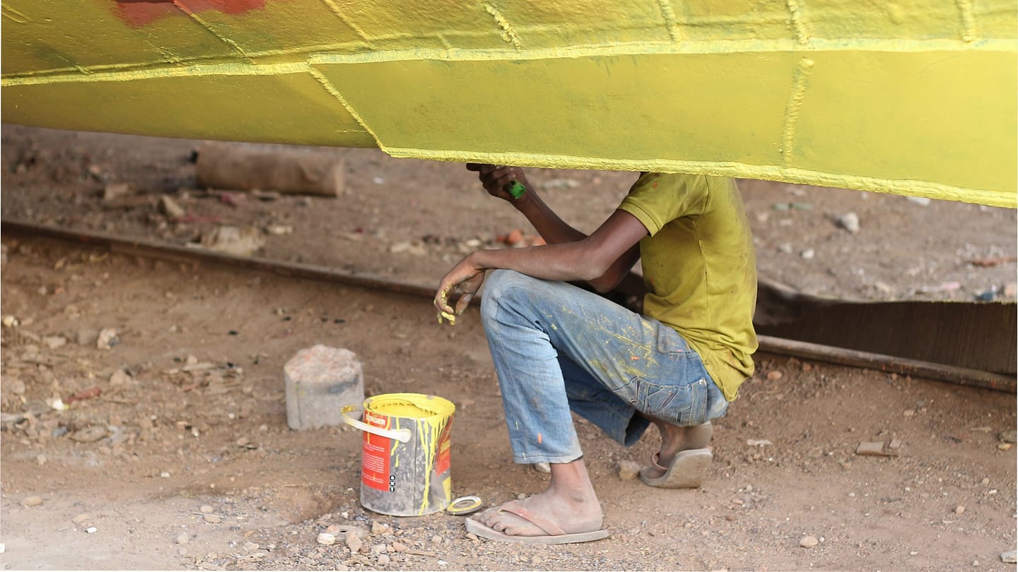 A worker paints the underside of a boat hull