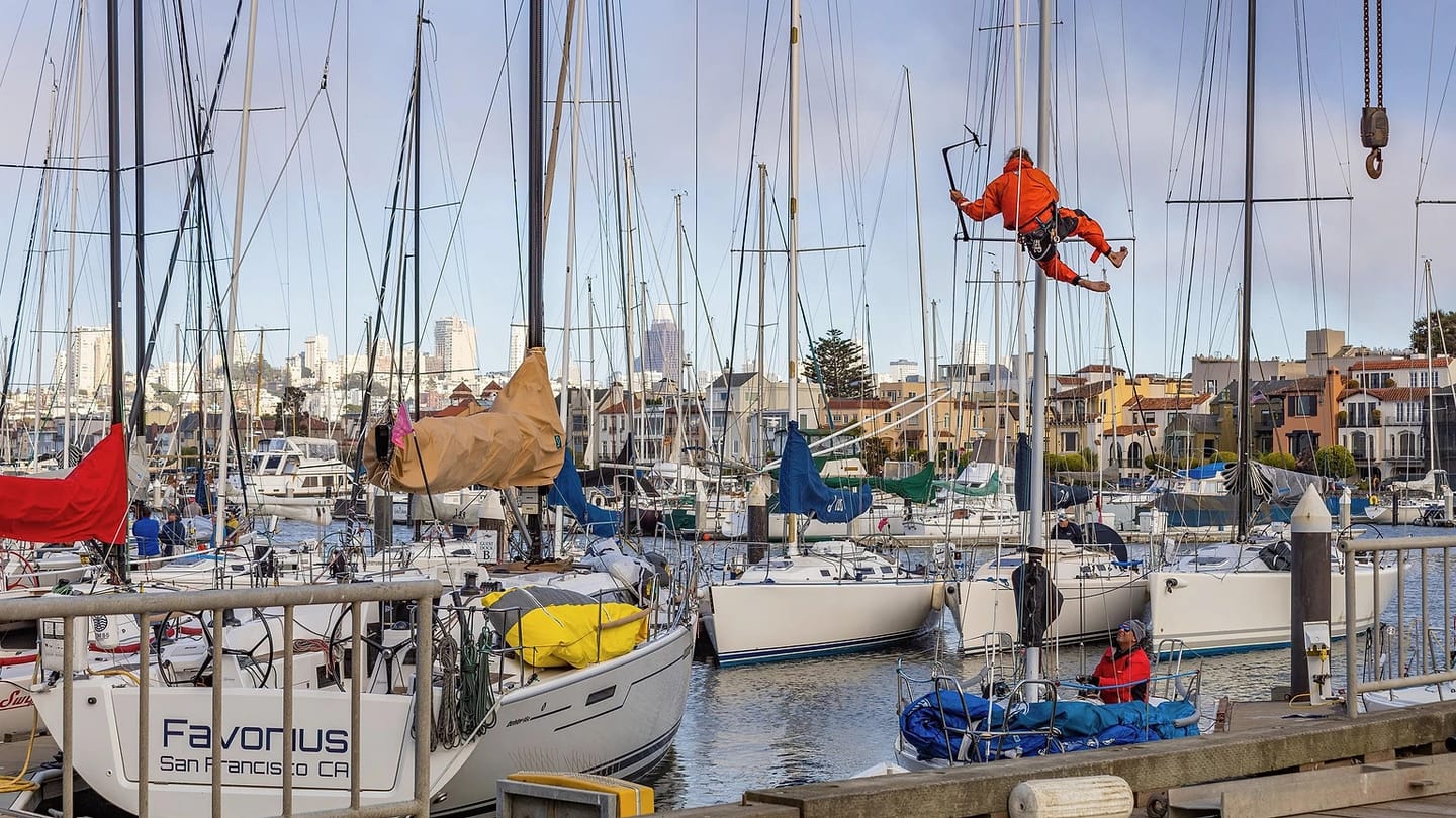 Person repairing a sailboat at a marina
