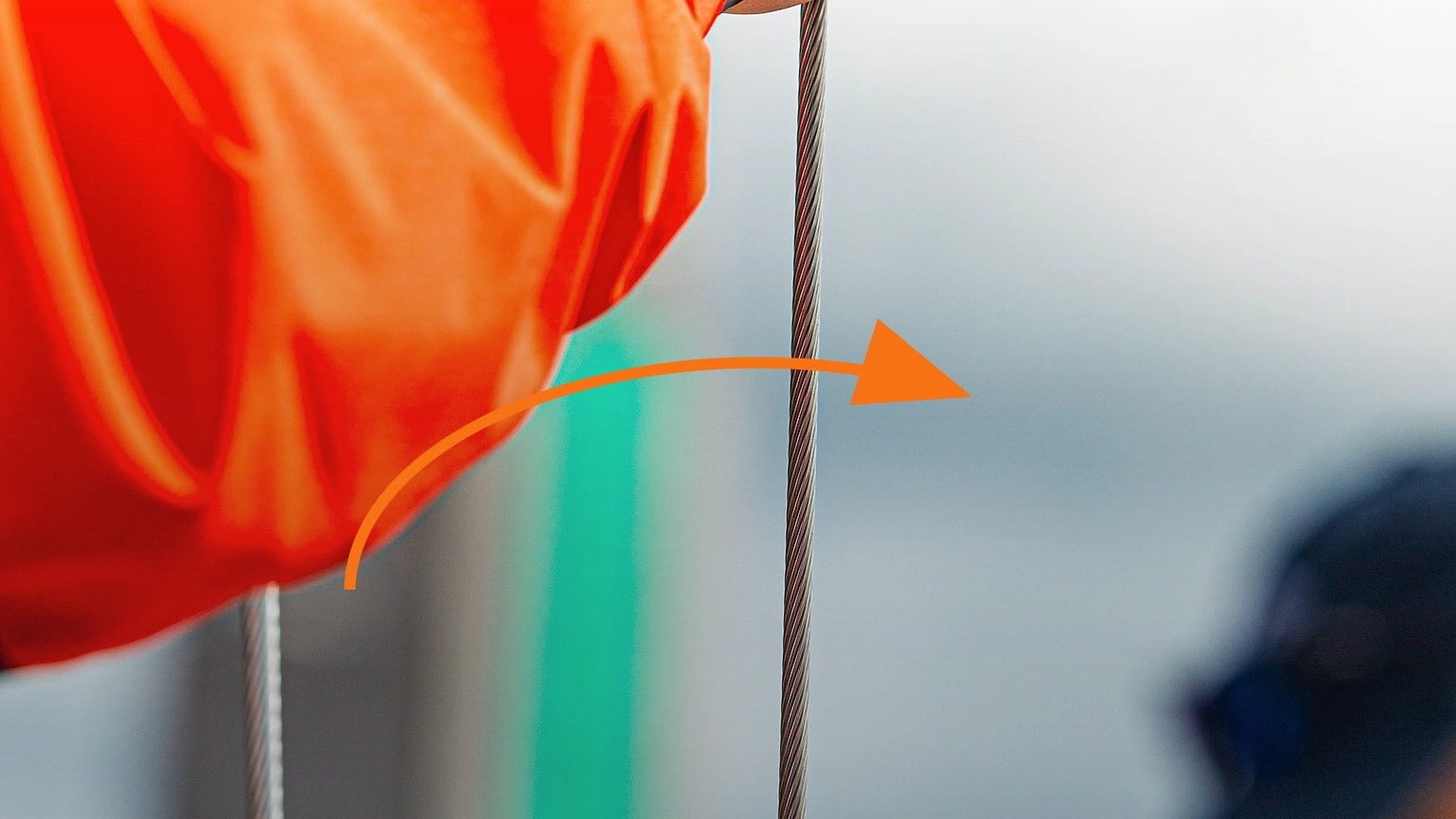 A close view of a sailing line beside bright fabric, with an arrow showing one controlled pull
