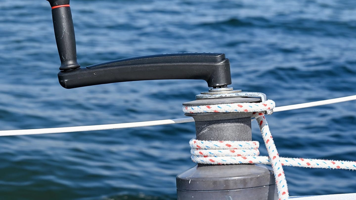 Metal sailboat winch with rope on a wooden deck