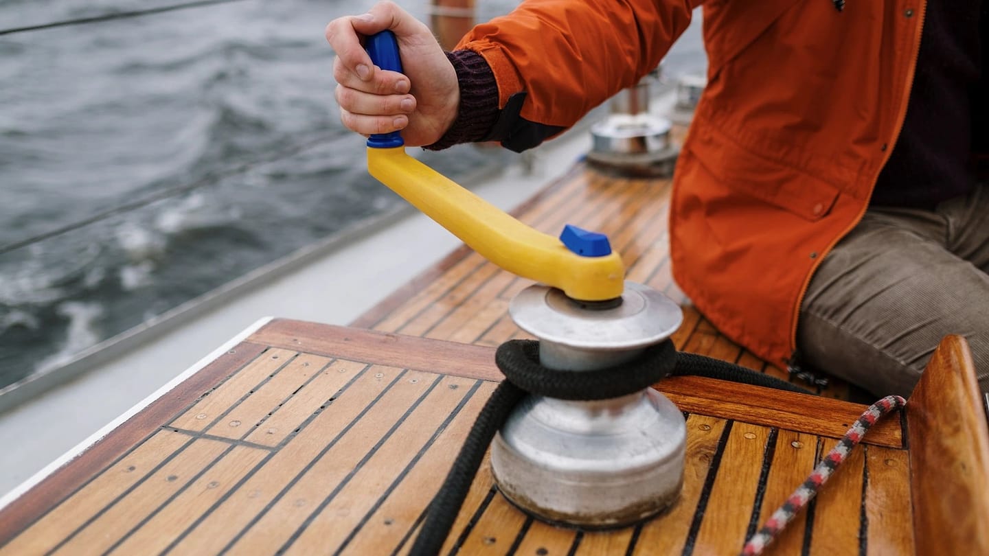 Sailor operating a winch on a wooden deck