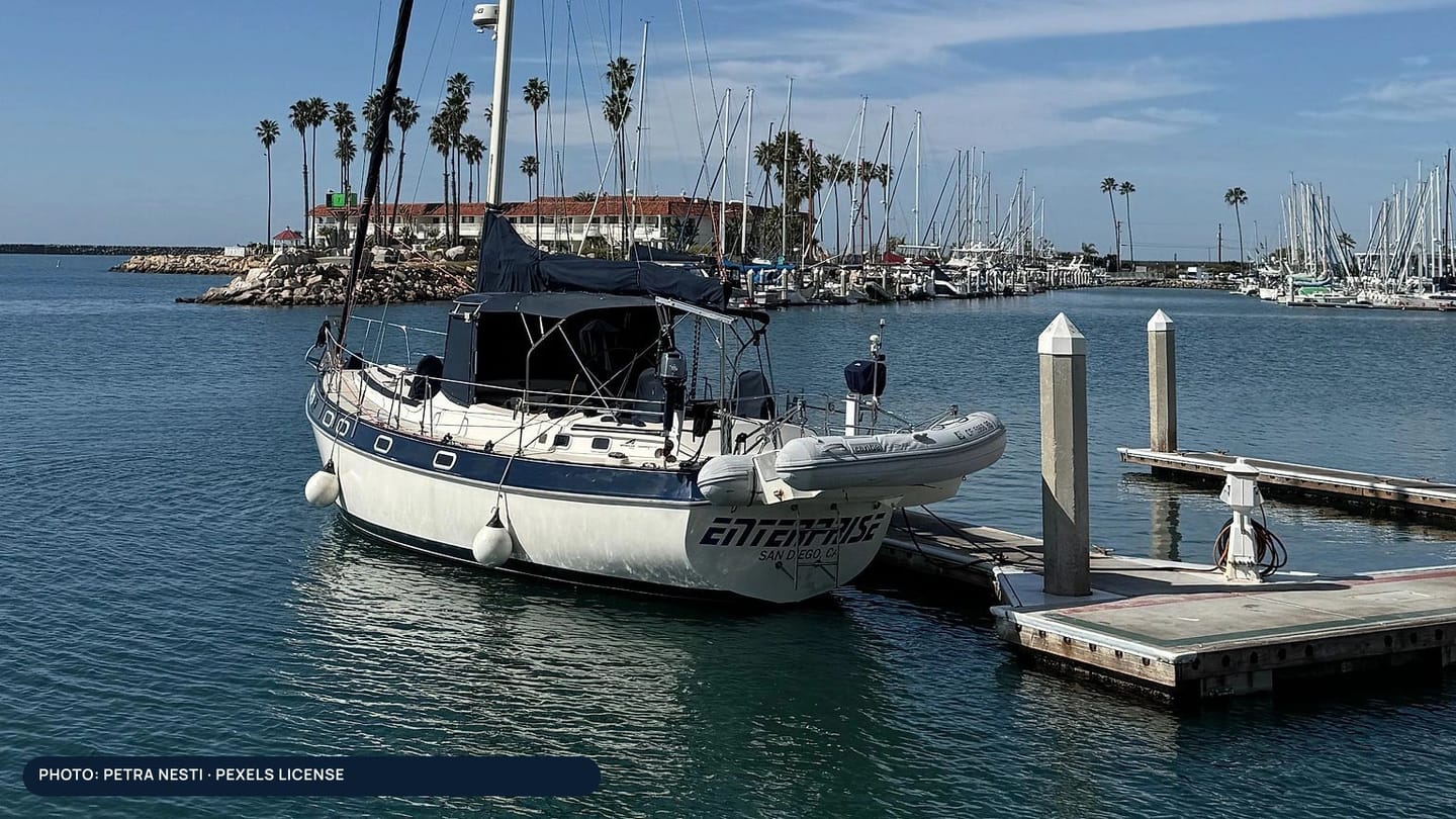 An inflatable dinghy secured beside the stern of a cruising sailboat