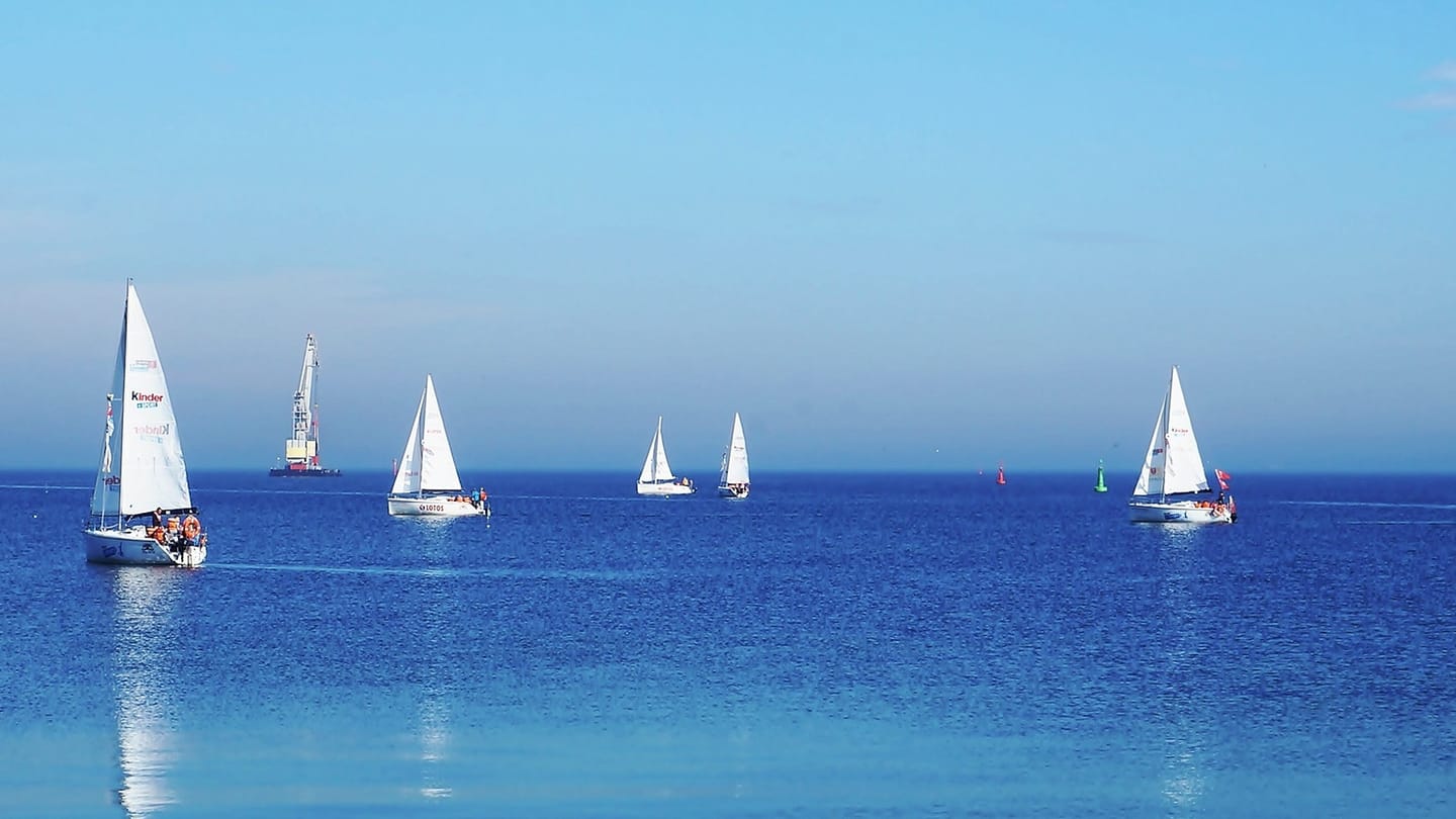 Sailboats travelling along a marked coastal channel