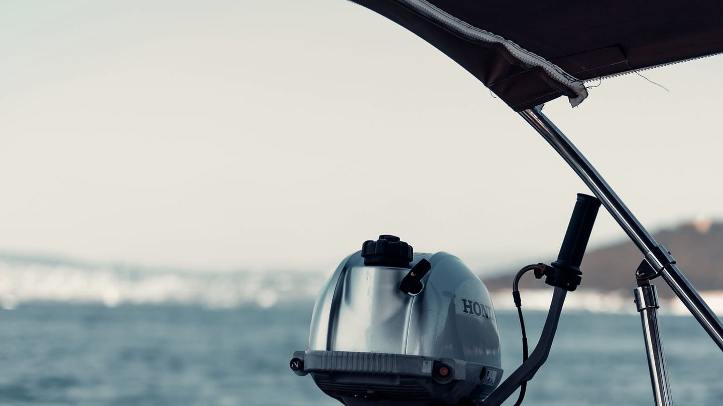 An outboard motor is mounted at the stern of a boat on calm water.