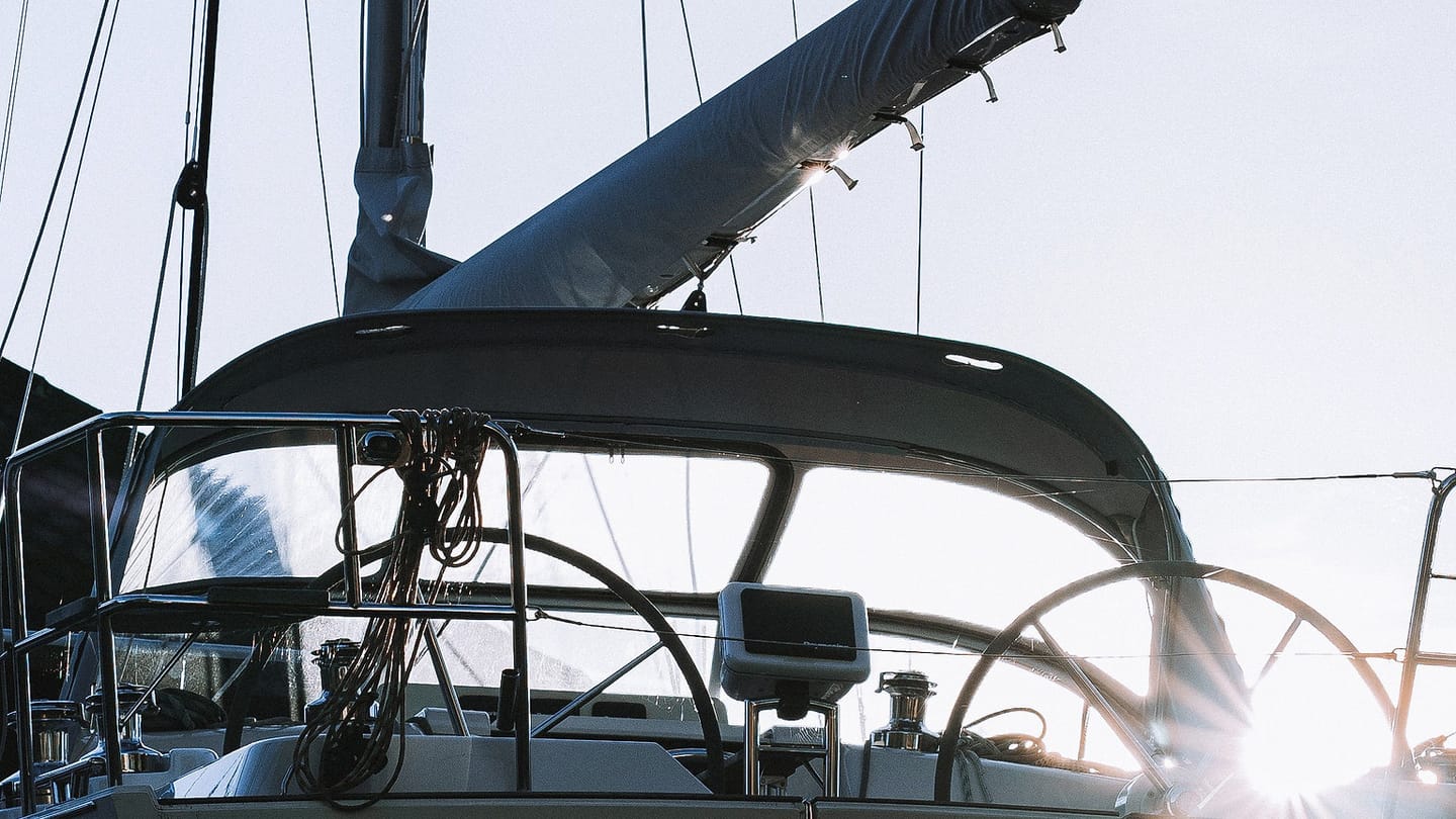 A white sailboat lies at a dock with its stern and cockpit visible.