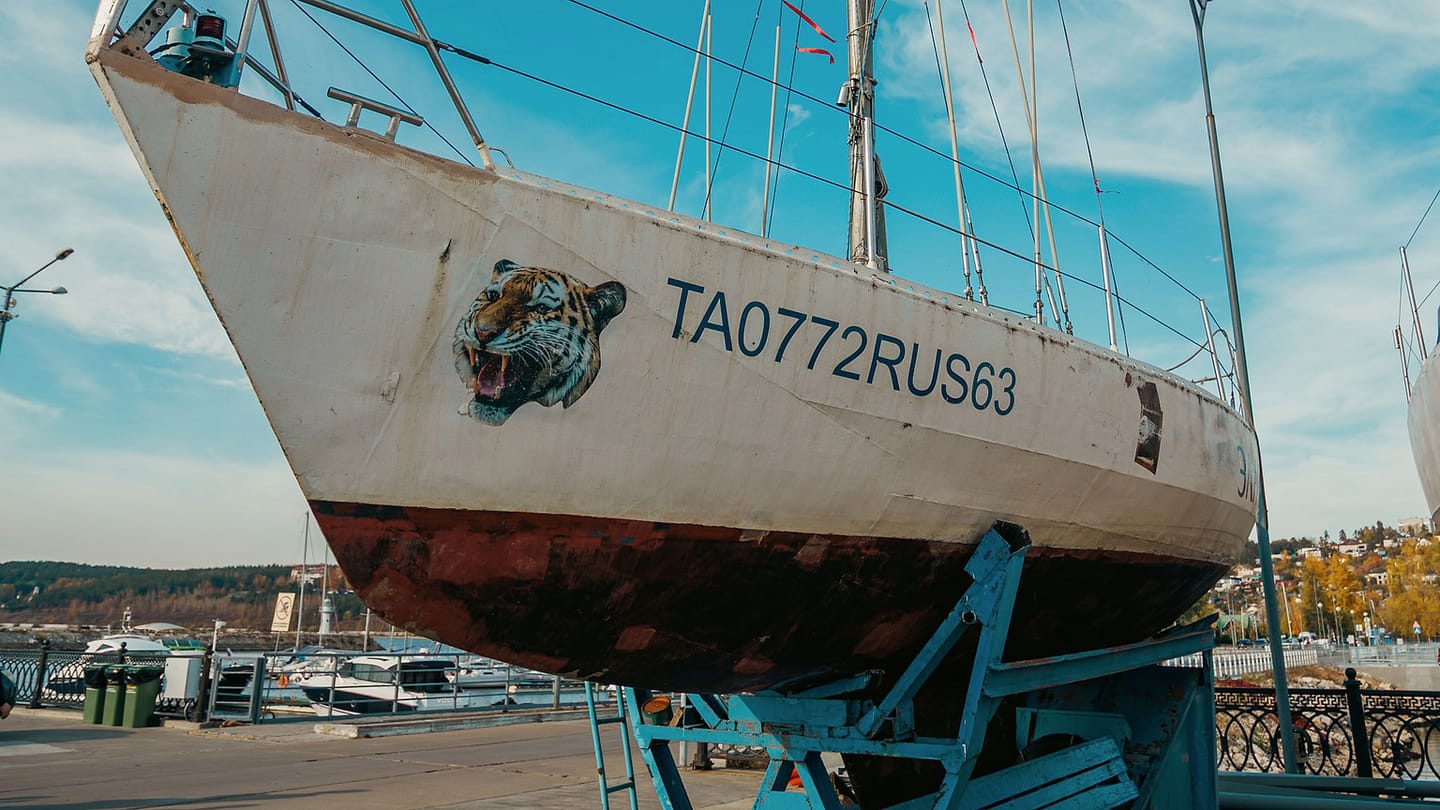 A sailboat stands in a yard with its keel and underwater hull exposed.