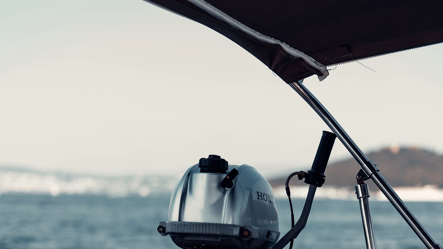 An outboard motor cowling and control cable are visible beneath a stern canopy.
