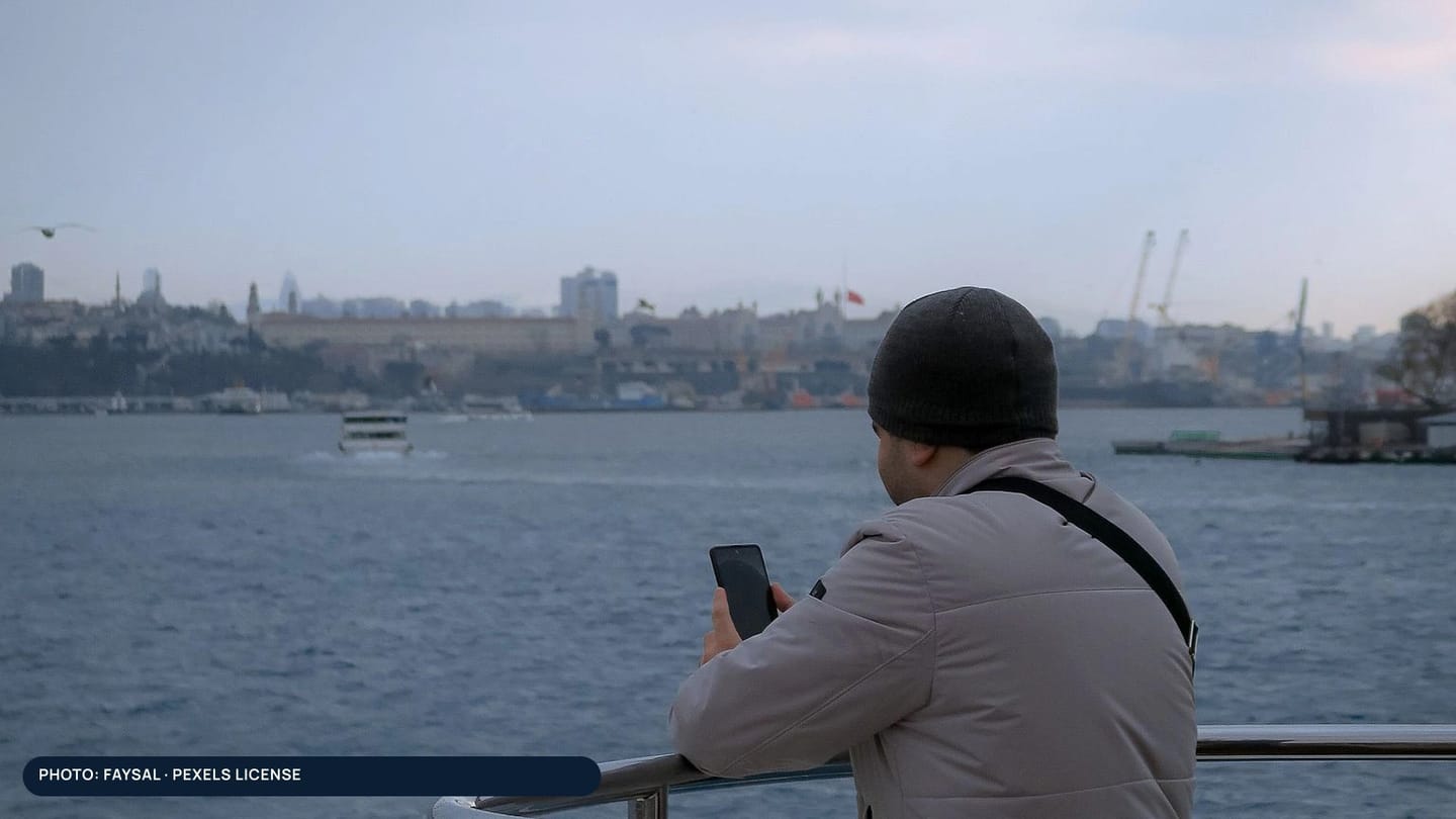 A person checking a phone from the deck of a boat