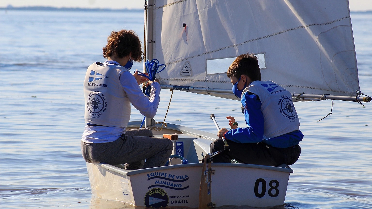 Two sailors handling a small dinghy on calm water