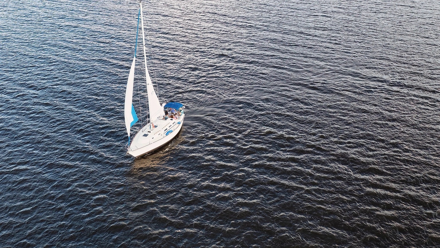Sailboat seen from above while crossing dark blue water