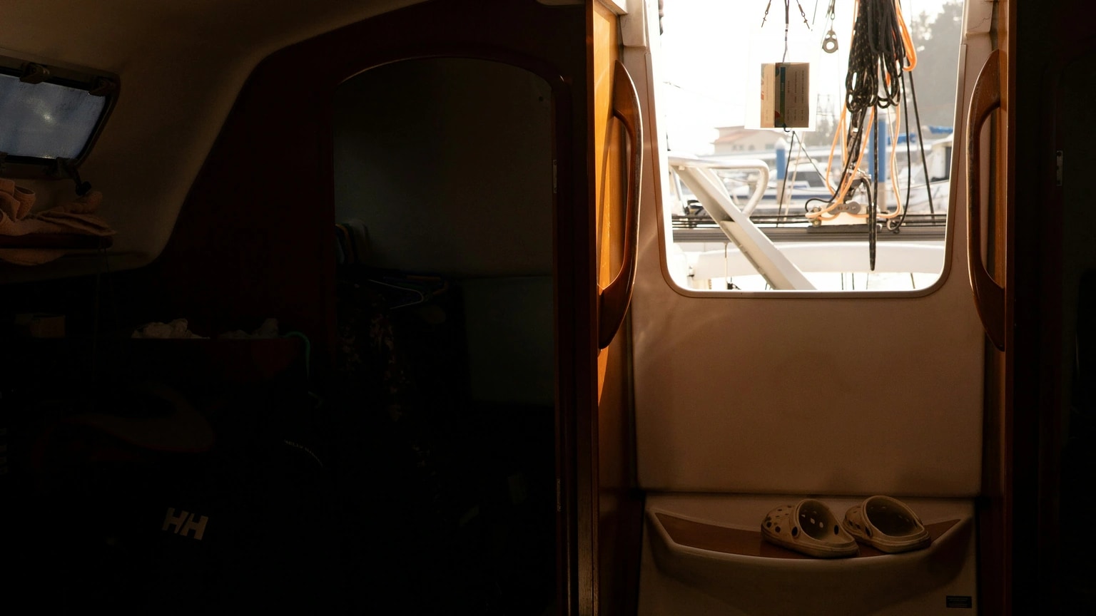 Sunlight enters a compact sailboat cabin through an open companionway