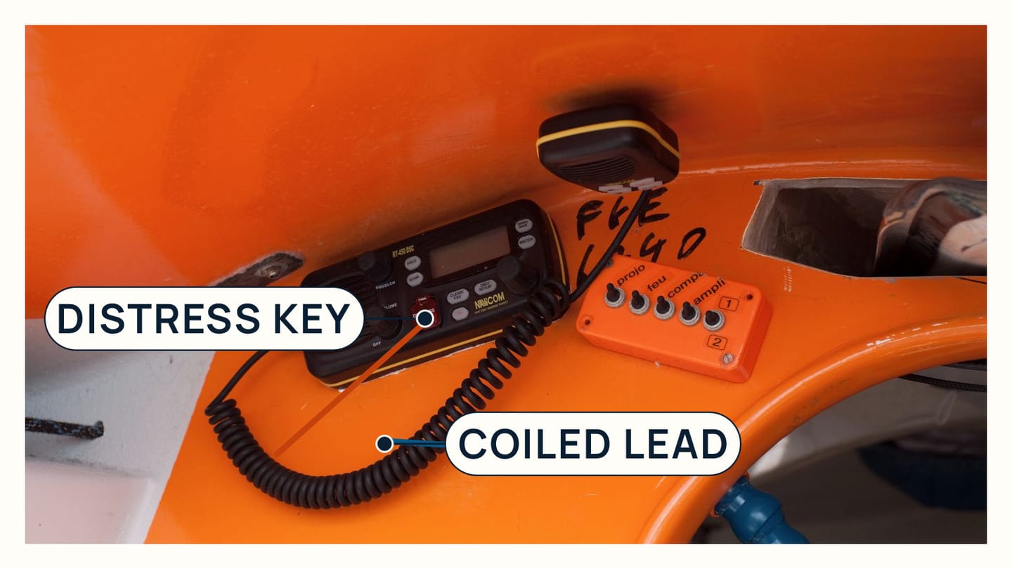 A fixed DSC VHF panel with a red distress key and coiled microphone lead
