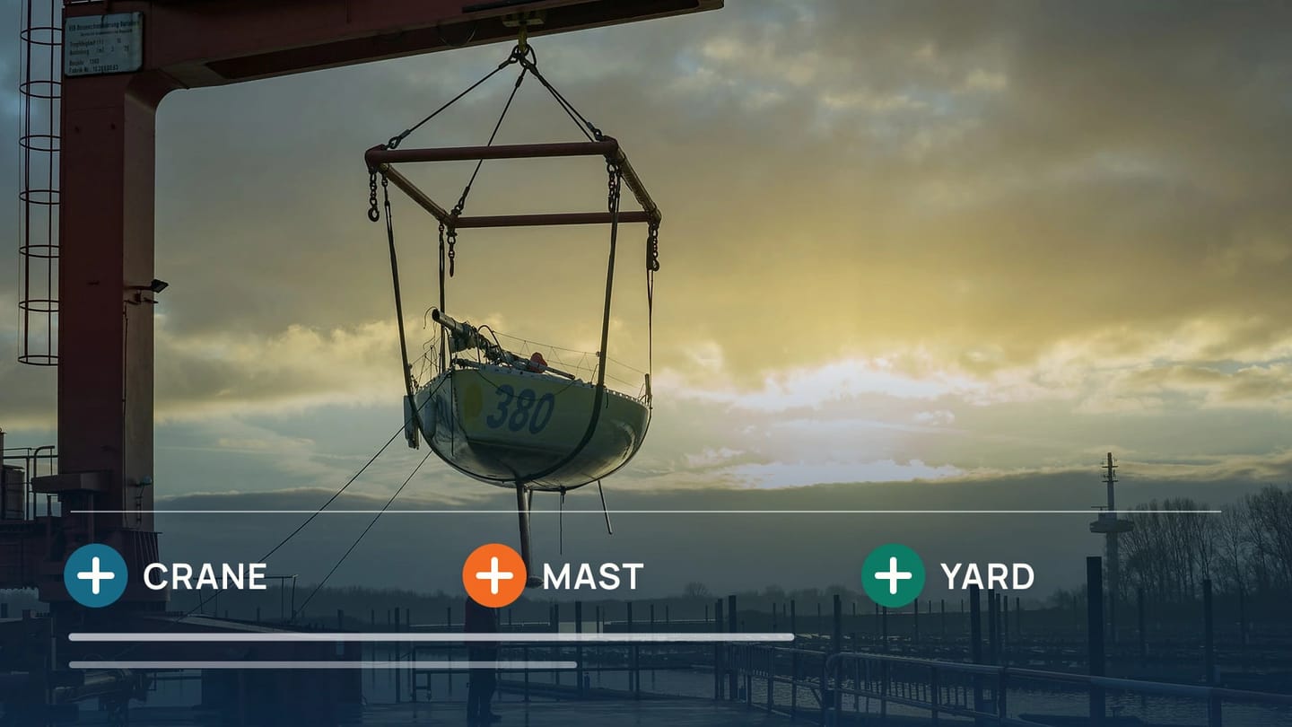 Sailboat mast handled by a yard crane beside a boat