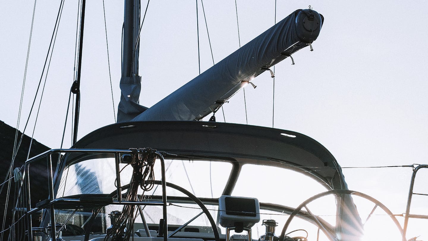 A white sailing yacht rests at a marina beside other boats.