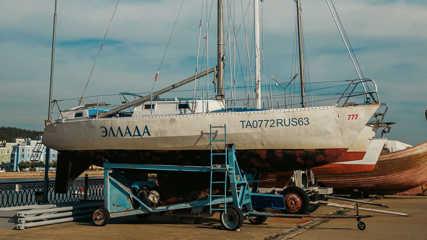 A sailboat rests ashore on dry-dock supports.