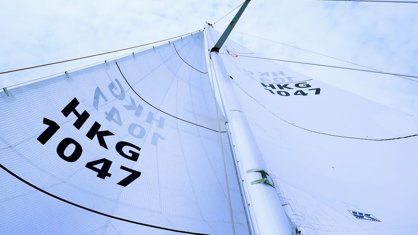 A close view shows a white headsail and its seams filled by wind.