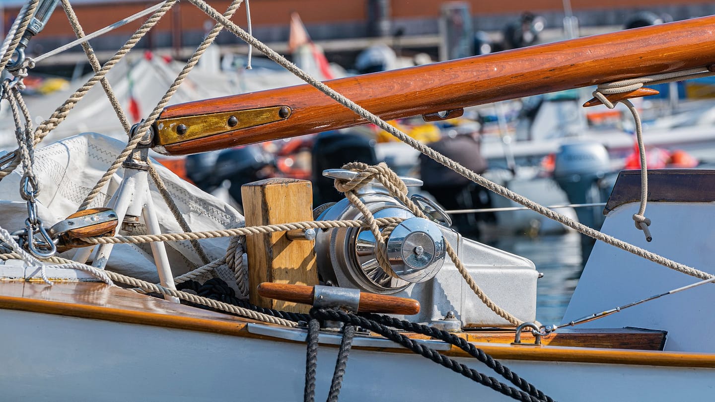 Sailboat lines, a block, and metal deck fittings fill the foreground.