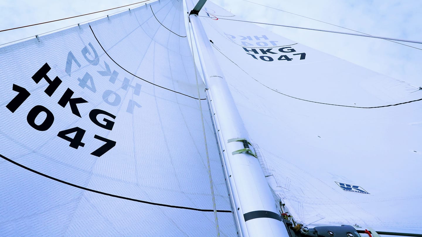 A white headsail curves under wind above the side deck of a yacht.
